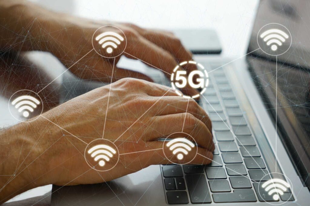 Person using a laptop with digital 5G and Wi-Fi symbols overlayed, representing advanced cybersecurity practices for next-generation networks.