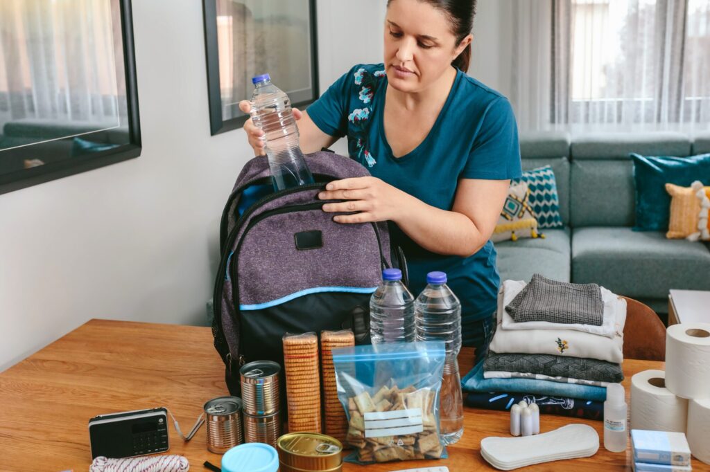 A woman organizing and packing an emergency preparedness bag at home.