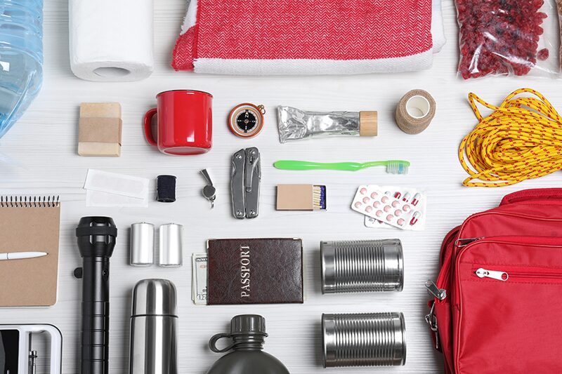 A bag on a table with emergency supplies laid out beside it.